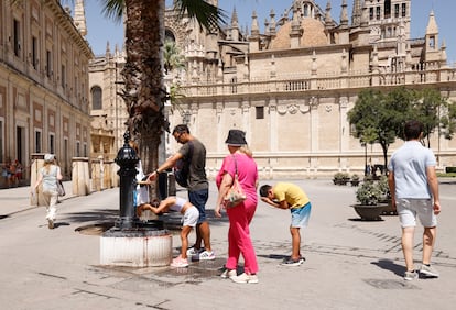 Varias personas alivian el calor en una fuente de Sevilla, este lunes 21 de agosto. 