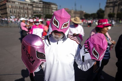 La manifestación inició desde las nueve de la mañana, cuando los asistentes comenzaron a teñir el Zócalo de rosa, color oficial del Instituto Nacional Electoral (INE) y por lo tanto símbolo, de la protesta. En la imagen, un manifestante sostiene máscaras de luchadores con frases en apoyo al órgano electoral bordadas a sus costados. 