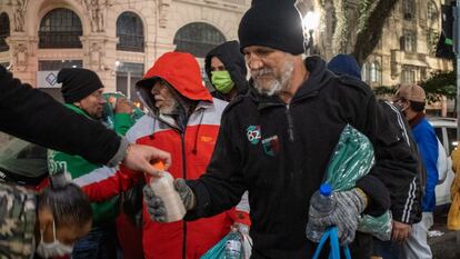 Apesar do frio, muitas pessoas foram às ruas para distribuir alimentos, cobertores e agasalhos. Na imagem, um morador recebe uma garrafa de bebida quente de um voluntário.