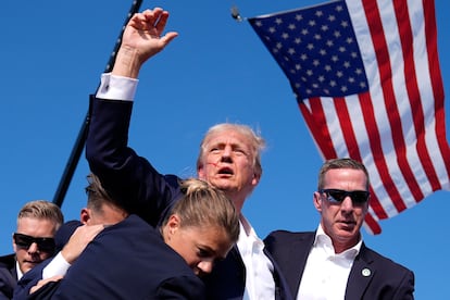 Trump se retira del mitin en Butler (Pensilvania) levantando el puño, rodeado por agentes del Servicio Secreto y en aparente buen estado.

