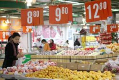 Una clienta selecciona piezas de fruta en un supermercado. 