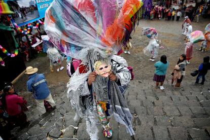 Un hombre vestido para danzas tradicionales camina durante una fiesta patronal en honor a Santo Tomás, en Chichicastenango (Guatemala).