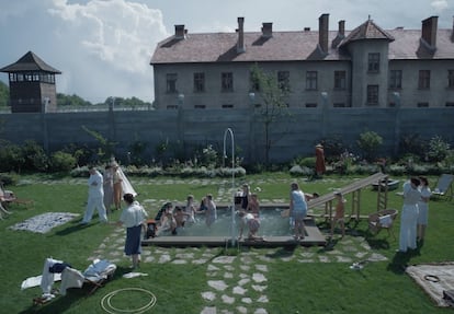 A scene from 'The Zone of Interest' showing the Auschwitz commander's garden with the prison camp in the background.