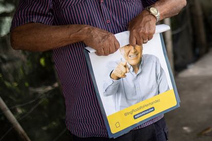 Un partidario enrolla un cartel con el candidato presidencial Rodolfo Hernández un día antes de la segunda vuelta presidencial del país, Bucaramanga, el 18 de junio de 2022.