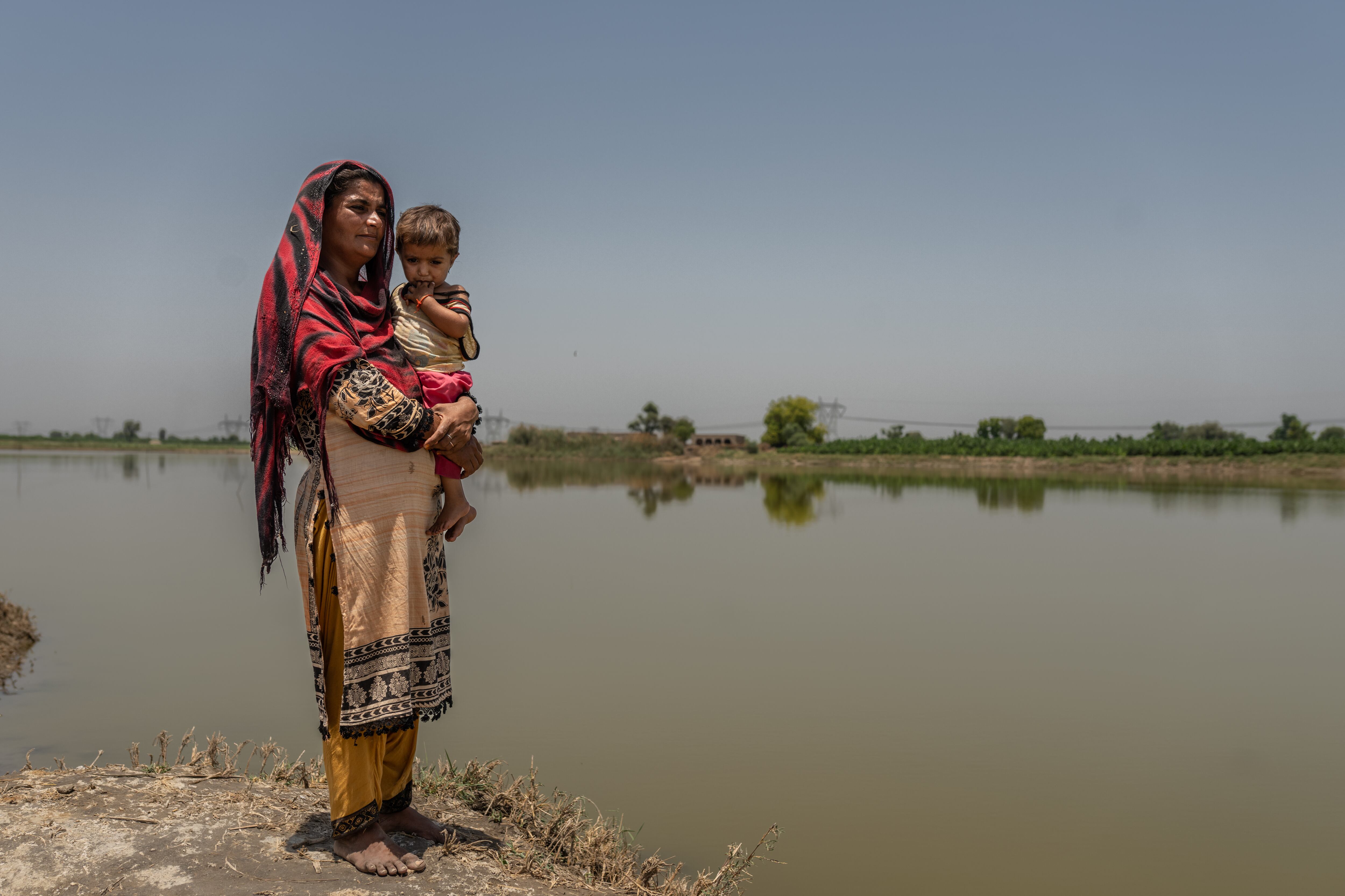 Benazir, de 30 años, junto a su hija, Oumara, de tres, al lado del agua aún estancada tras las devastadoras inundaciones que comenzaron en junio de 2022 en Pakistán, y que causaron más de un millar de muertos. Benazir perdió un hijo. Ahora, su hija de ocho años, Uzma, ha tenido que abandonar la escuela para trabajar en el campo, mientras la familia lucha por llegar a fin de mes. 