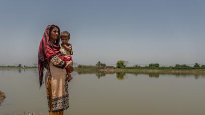Una madre sostiene en brazos a su bebé junto a las áreas inundadas en Village Balocho Zardari, Shaheed Benazir Abad, Nawabshah, Sindh, Pakistán.