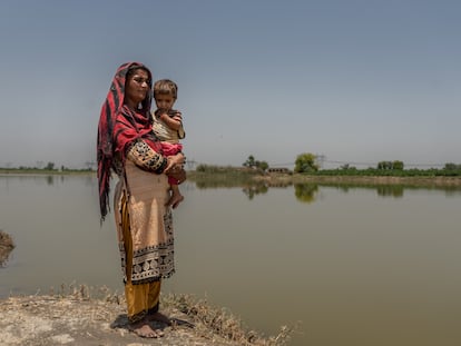 Una madre sostiene en brazos a su bebé junto a las áreas inundadas en Village Balocho Zardari, Shaheed Benazir Abad, Nawabshah, Sindh, Pakistán.