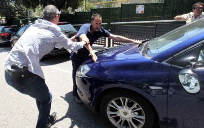 Un polic&iacute;a de paisano intenta sacar a un manifestante de cap&oacute; del coche del consejero. 