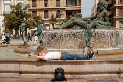 Un hombre descansa al sol en la fuente de la plaza de la Virgen de Valencia, el pasado viernes.