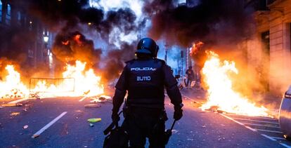 Un policía camina por via Laietana entre barricadas ardiendo.