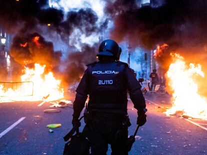 Un policía camina por via Laietana entre barricadas ardiendo.