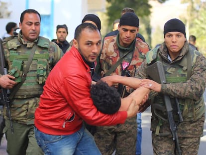 Un ciudadanos y vario soldados llevan a un joven que trat&oacute; de quemarse a  lo bonzo en una protesta el viernes en Kaser&iacute;n.