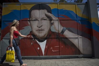 Una mujer camina frente a una puerta pintada con la imagen de Chávez en Caracas.