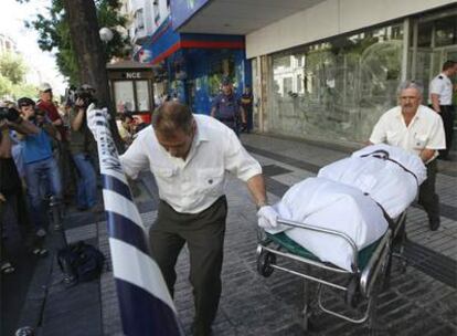 Dos operarios retiran el cadáver encontrado en un local de la calle de Alcalá.