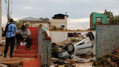 Escombros y un auto volcado junto a residentes luego de que un ciclón extratropical azotara ciudades del sur, en Roca Sales.