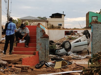 Escombros y un auto volcado junto a residentes luego de que un ciclón extratropical azotara ciudades del sur, en Roca Sales.