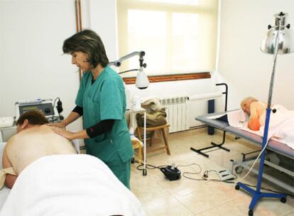 Una fisioterapeuta atiende a dos mujeres en el centro de mayores de Boimorto.