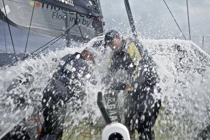 Dos tripulantes del equipo Brunel trabajan en la cubierta del barco batida por las olas durante la segunda etapa de la vuelta al mundo a vela. Océano Índico, 29 de noviembre de 2014.