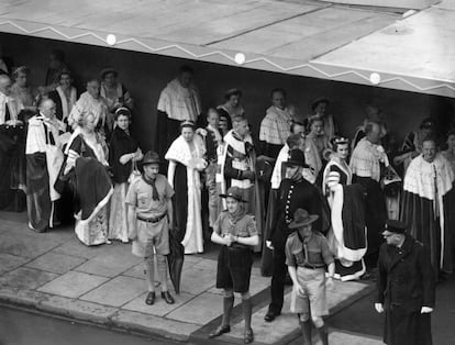 Peers and peeresses in their robes enter Westminster Abbey to take their places for the Coronation ceremony. Scouts seen on the pavement are there to open car doors.  