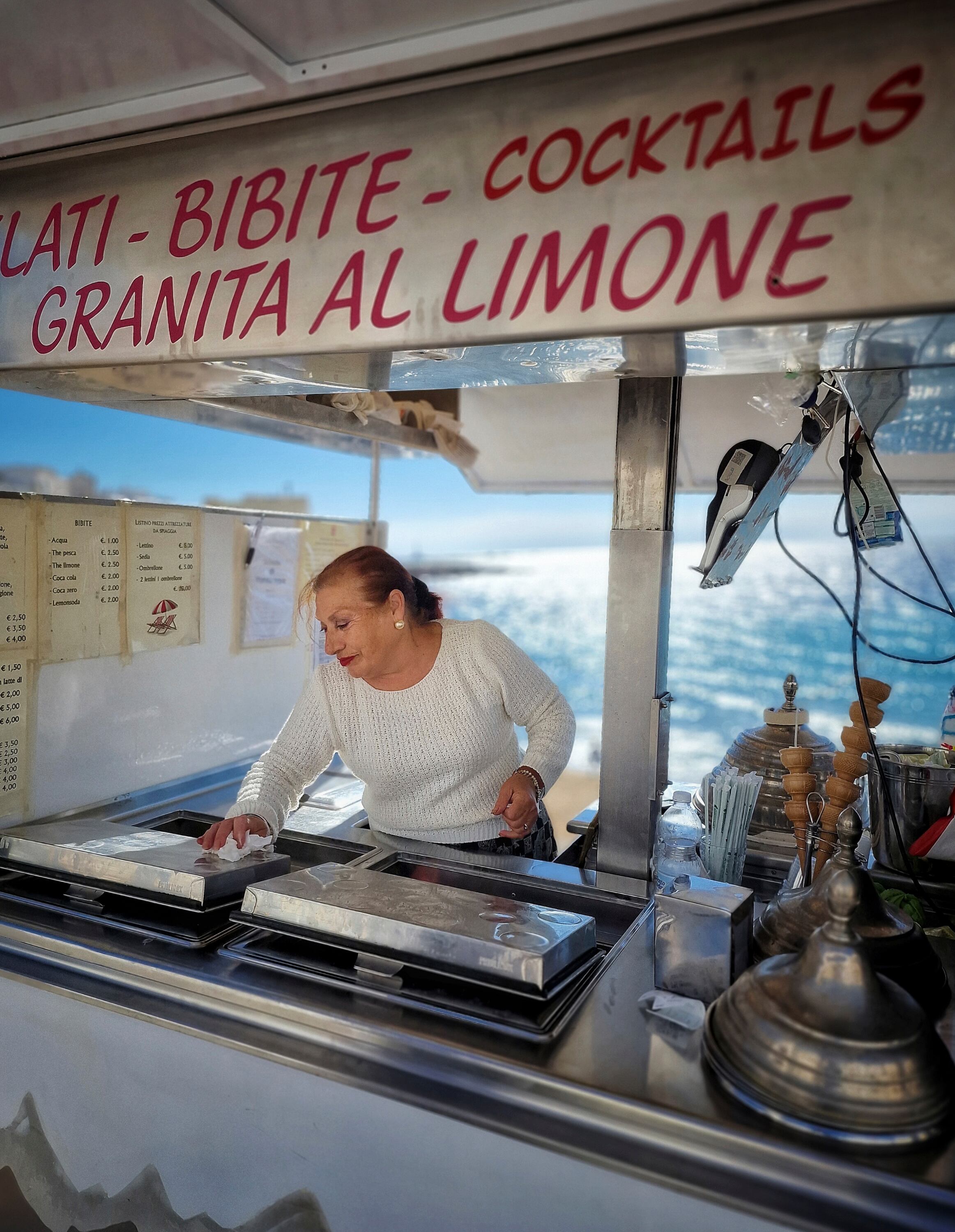 Una mujer atiende un puesto de helados y bebidas junto al Mediterráneo, en la costa de Puglia.