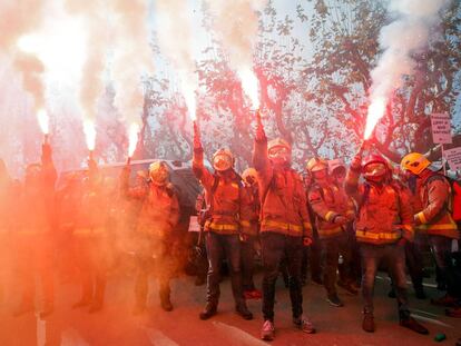 Un grupo de bomberos alza bengalas durante la protesta frente al Parlament.