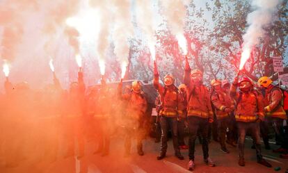 Un grupo de bomberos alza bengalas durante la protesta frente al Parlament.