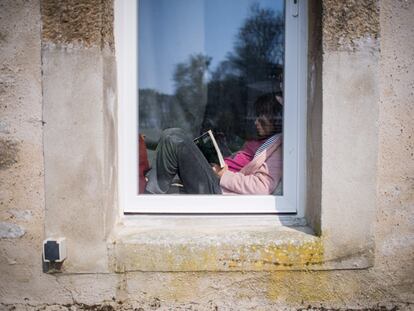 Menina lê dentro de casa em Lavau-sur-Loire, na França, durante quarentena.