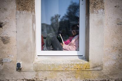 Menina lê dentro de casa em Lavau-sur-Loire, na França, durante quarentena.