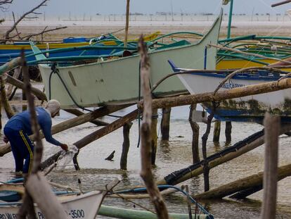 Un hombre lava su barca en el sur de la isla Samar, por donde han pasado el tifón Haiyán y la tormenta Hagupit.