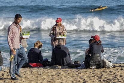 Venedors de mojitos a la platja de Barcelona. Al fons, un home practica surf.