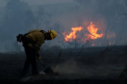 Un bombero trabaja para sofocar puntos calientes en el incendio forestal que afecta a las zonas vitivinícolas de California.