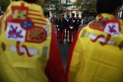 Desde una hora antes del inicio de la parada militar han ido llegando las autoridades a la plaza de Lima de Madrid, donde se ha ubicado la tribuna principal para el seguimiento de este acto. En la imagen, al fondo, militares de la Guardia Real por las calles de Madrid.