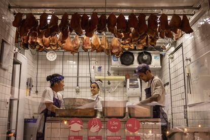 Empleados del restaurante A casa do Porco trabajan en una sala con un escaparate que da a la calle. 