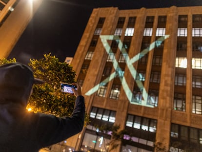 Una persona fotografía el nuevo logo de Twitter, proyectado en la sede de San Francisco (California).