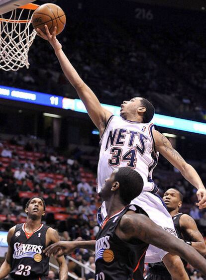 El jugador Devin Harris (c) de los Nets de Nueva Jersey intenta encestar con la marca de Royal Ivey (d) y Louis Williams (i) de los 76ers de Filadelfia