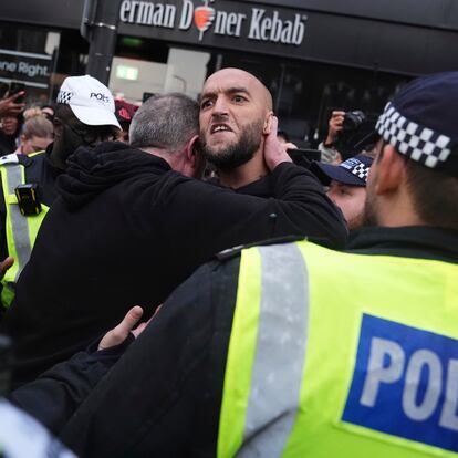 An anti-immigration protester, center, speaks to police officers in North Finchley, London, Wednesday, Aug., 7, 2024, asnanti-immigration groups targeted dozens of locations throughout the country following a week of rioting and disorder fueled by misinformation over a stabbing attack against young girls. (PA via AP)