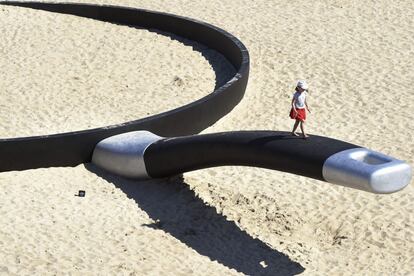 Una niña camina por el mango de una sartén gigante, obra del artista australiano Andrew Hankin titulada "Nos estamos friendo aquí" que se expone en la playa de Tamarama beach, en Sídney (Australia).
