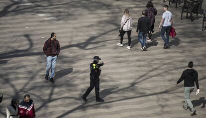 Un agent, diumenge, adverteix que no es pot passejar per la Rambla de Barcelona.