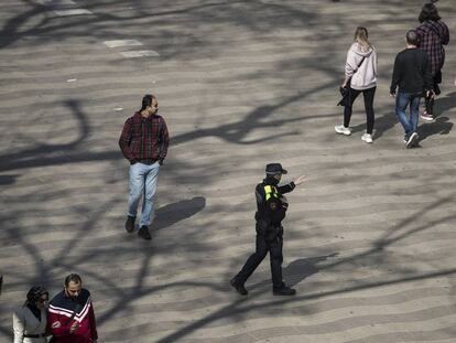 Un agent, diumenge, adverteix que no es pot passejar per la Rambla de Barcelona.