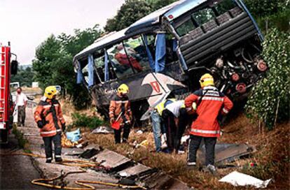 Los bomberos inspeccionan el lugar en el que quedó el autocar tras la colisión con el camión.