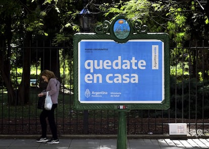 Mulher passa diante de um cartaz do Governo pedindo à população que não saia às ruas como prevenção contra o coronavírus.