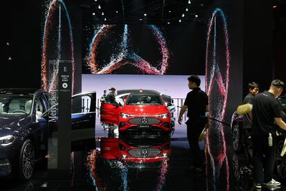 Trabajadores limpian automóviles en un stand de Mercedes-Benz.