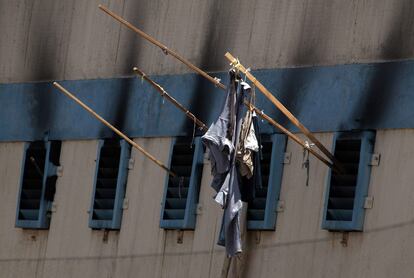 Ventanas quemadas y ropa de reclusos cuelgan,  a modo de bandera,  de la cárcel de San Miguel en Santiago), una sobrepoblada prisión del sur de la capital.