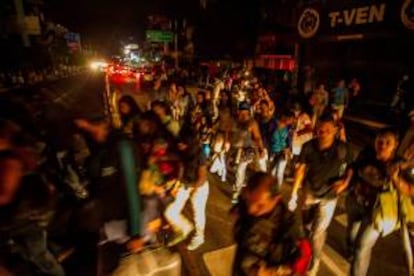 Transeúntes fueron registrados este lunes al circular por una calle a oscuras, durante un corte de energía eléctrica, en Caracas (Venezuela).