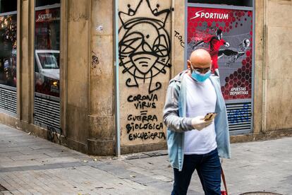 Un hombre camina frente a una pintada sobre la epidemia en el centro de Madrid.