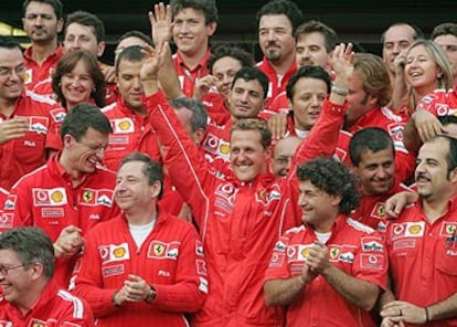 Michael Schumacher, junto a los miembros de su equipo, levanta los brazos en señal de victoria.
