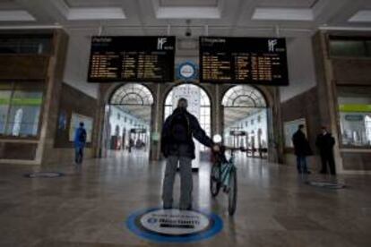 Un pasajero observa una pantalla con las llegadas y salidas previstas en la estación de trenes Santa Apolonia. EFE/Archivo