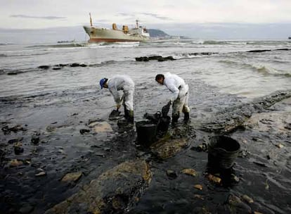 Dos trabajadores limpian la costa de fuel derramado por el buque embarrancado desde el domingo en Algeciras. La primera inspección realizada por el personal del Ministerio de Fomento al buque encallado en la bahía de Algeciras, ha concluído que en los tanques de doble fondo permanece parte del fuel que llevaba, sin que se pueda precisar aún la cantidad. La capacidad total del barco es de 350 toneladas.