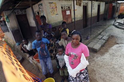 En esta foto tomada el 14 de agosto, Mamusu Kargbo, de 22 años y a la derecha de la imagen, y otros familiares de la víctima de ébola Musa Kamara miran cómo otros residentes del pueblo de Massessehbeh, en las afueras de Freetown, bailan y cantan para celebrar el fin de la cuarentena a la que fueron sometidos tras la muerte del chico.