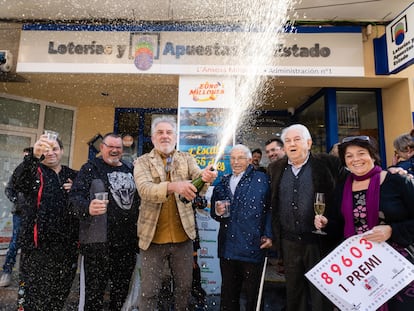 Los propietarios de la administración número 1 de L'Escala (Girona) celebran con agraciados y curiosos tras haber repartido todas las 40 series del primer premio de la Lotería de El Niño este viernes.